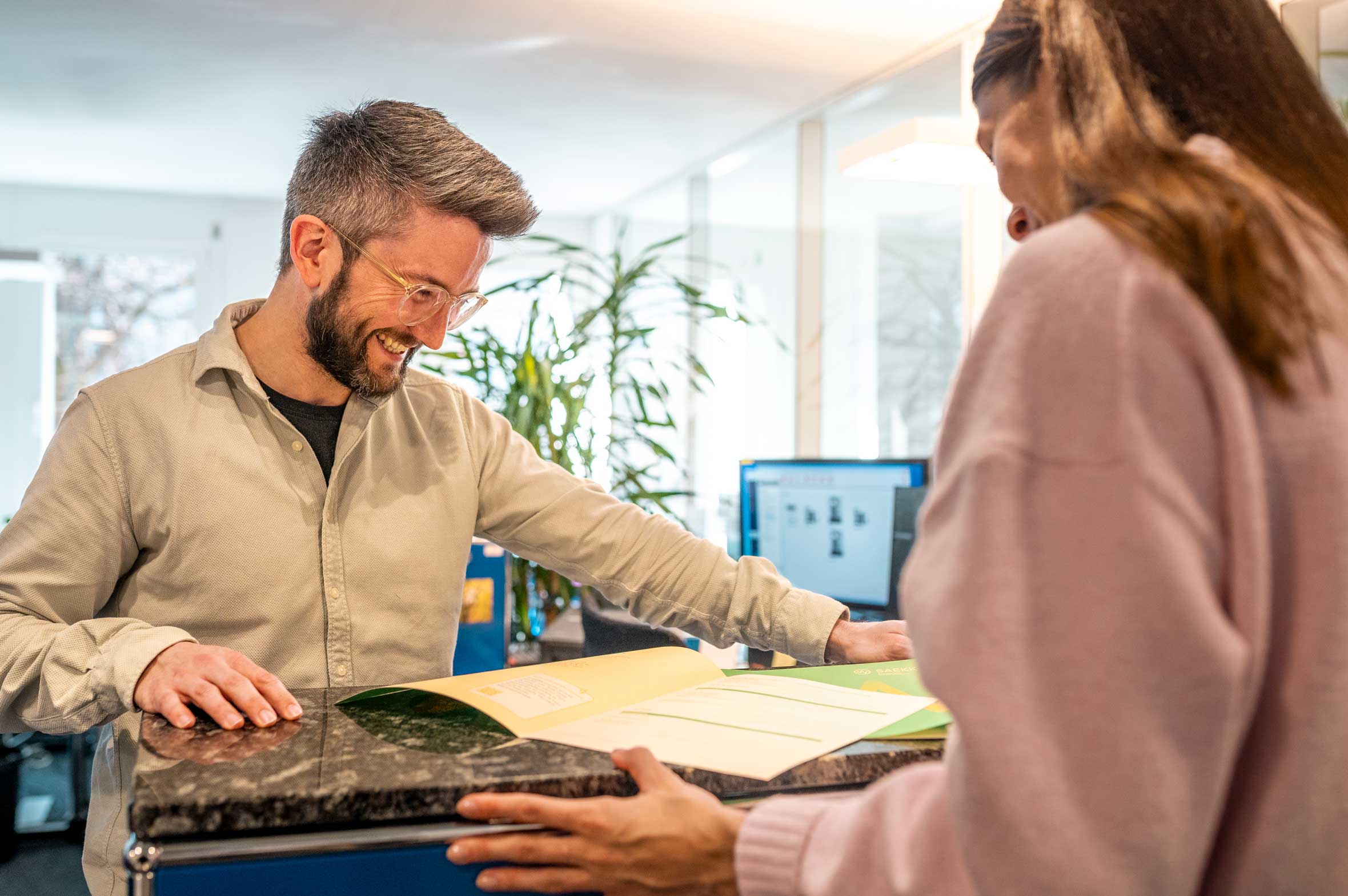 Mann zeigt einer Frau etwas in einer Broschüre